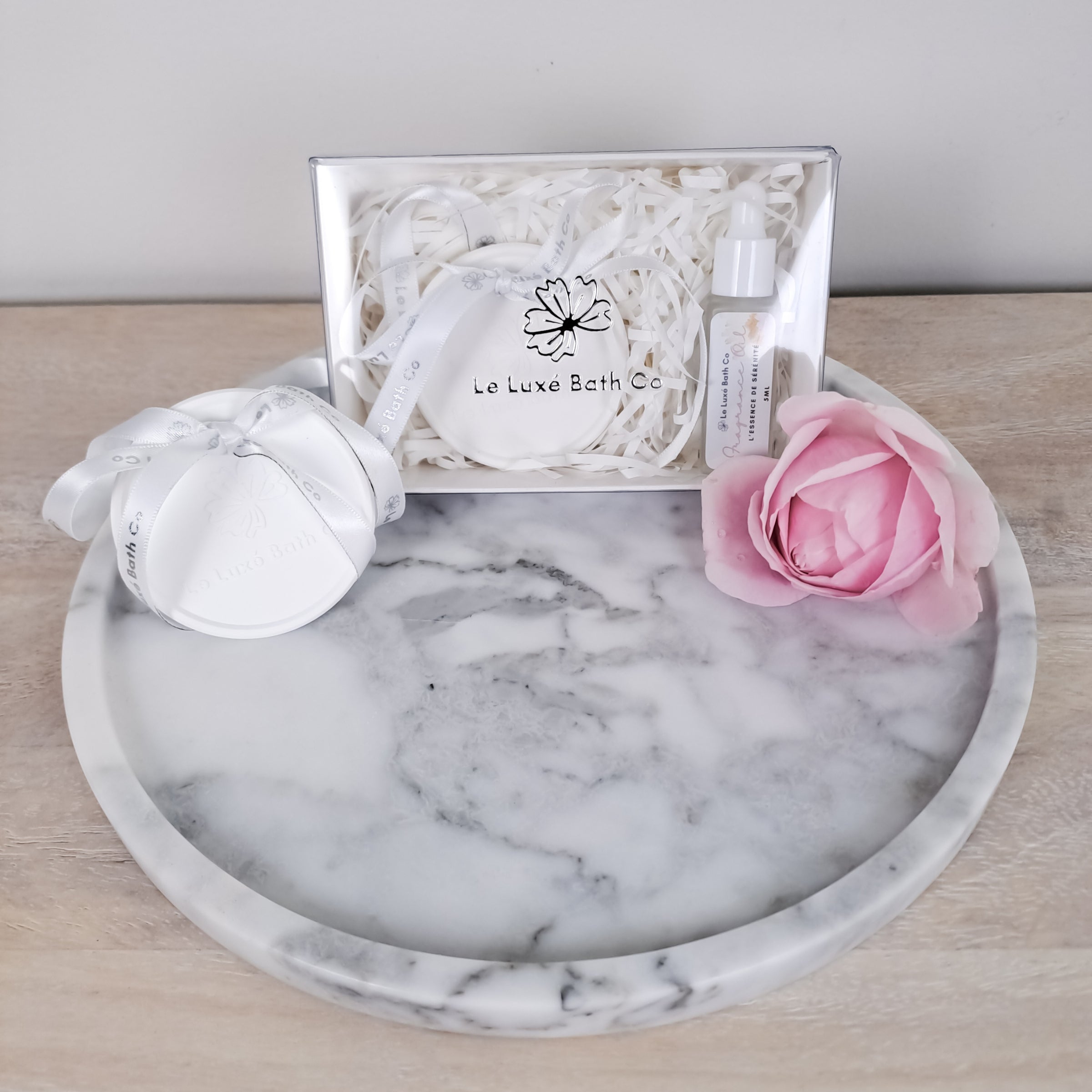 Marble tray with aroma disc and a pink rose on a wooden surface
