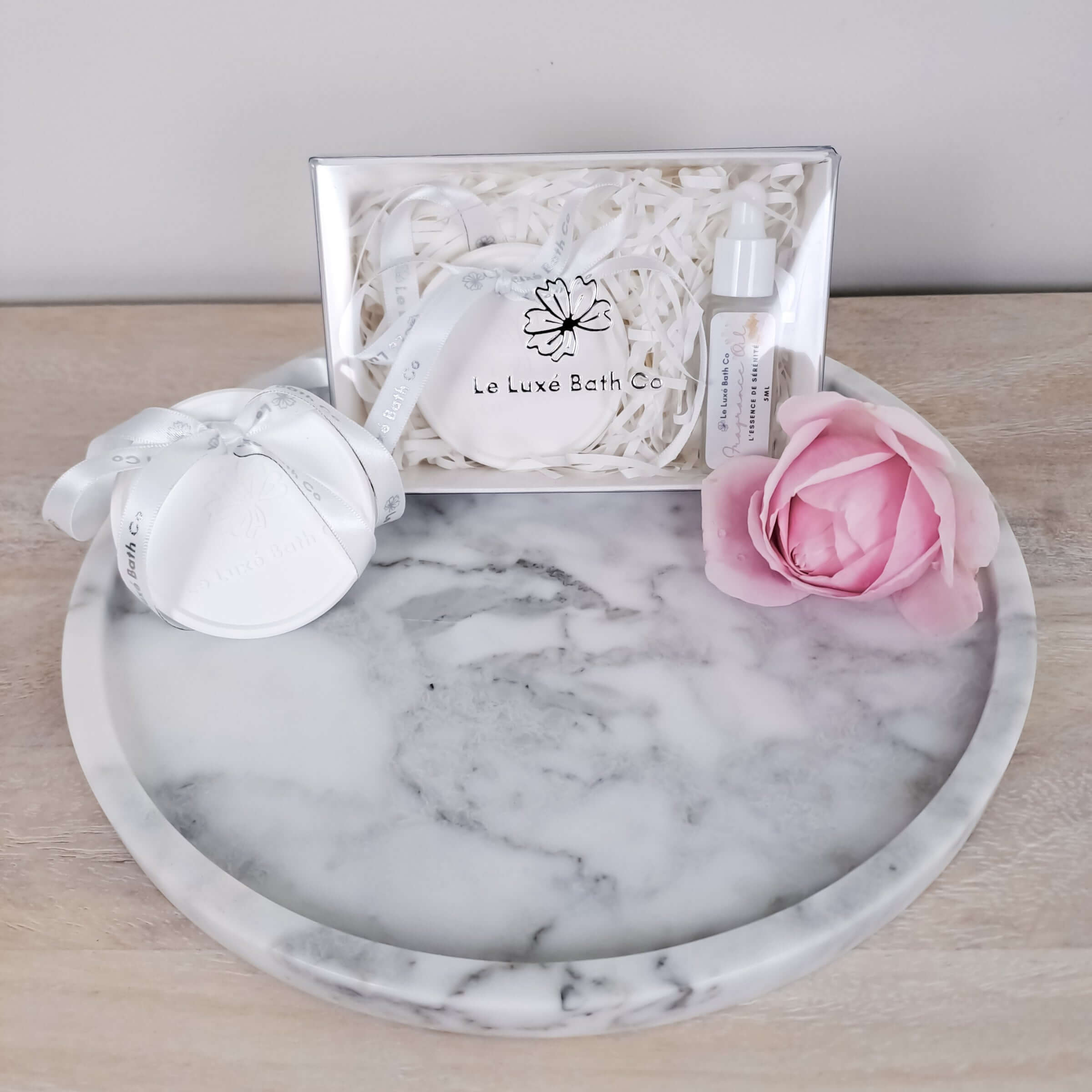 Marble tray with aroma disc and a pink rose on a wooden surface